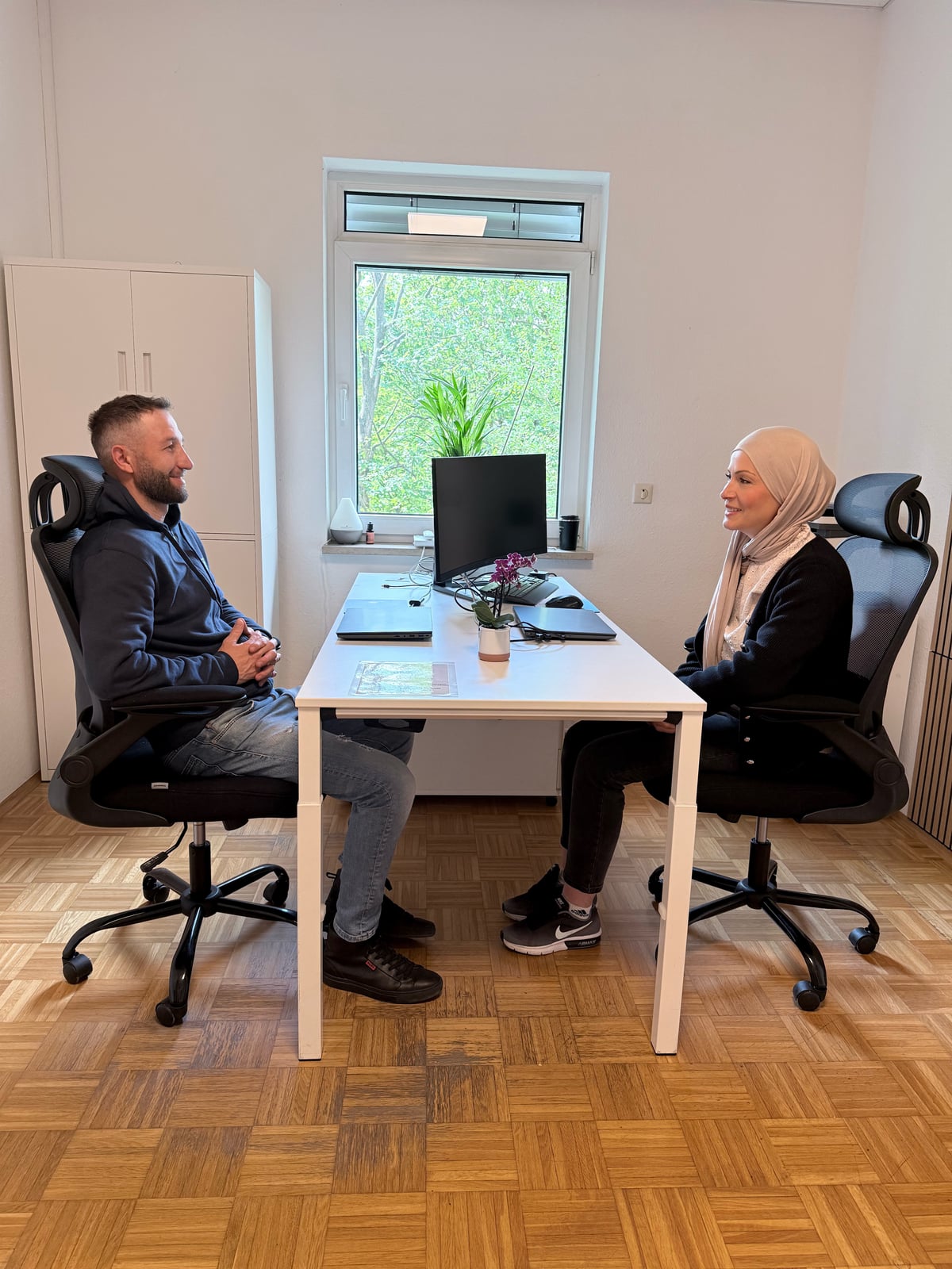 Patrick und eine Mitarbeiterin im persönlichen Beratungsgespräch am Bürotisch